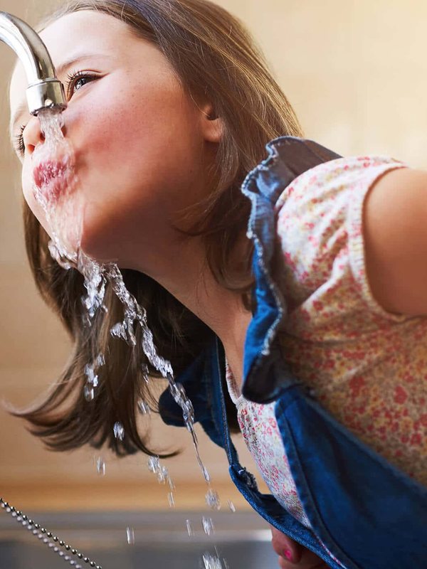 Niña bebiendo agua potable de Aguas Pirque